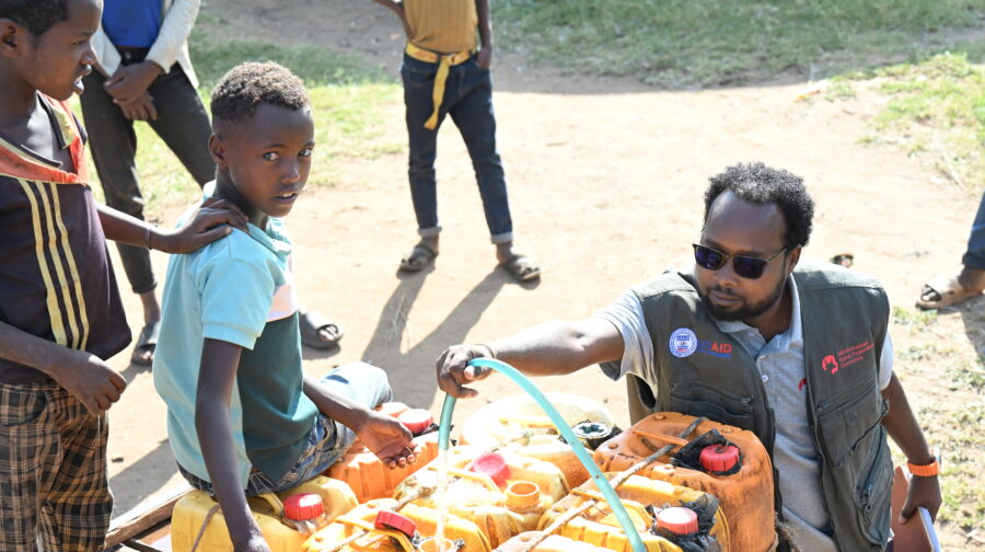 A staff member of VSF Germany in Ethiopia helps children fill water canisters.